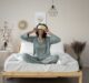 woman with eye mask sitting in bed smiling