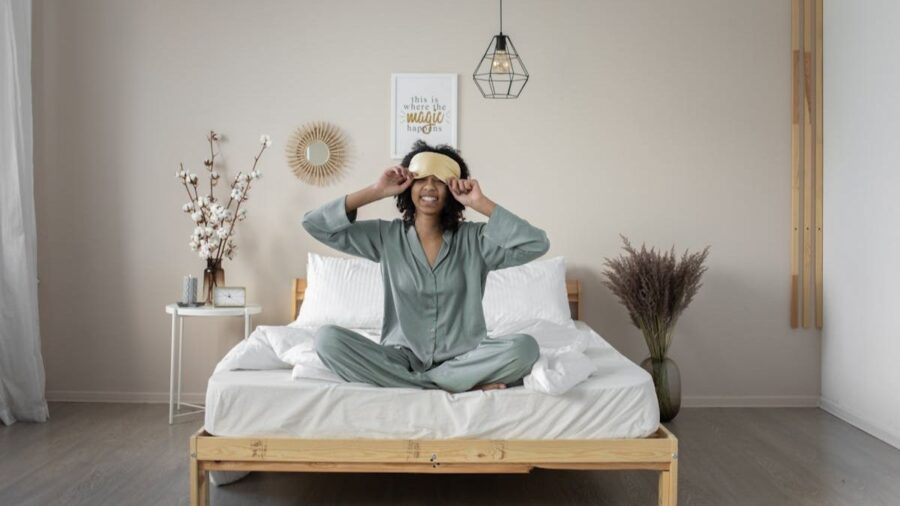 woman with eye mask sitting in bed smiling