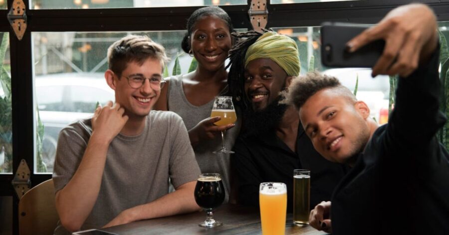 group of four people enjoying drinks and taking a selfie together