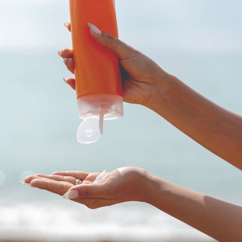 African American woman applying sunscreen