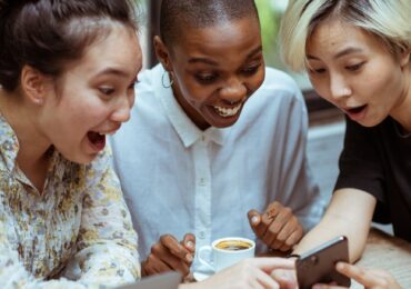 delighted female friends with laptop and smartphone